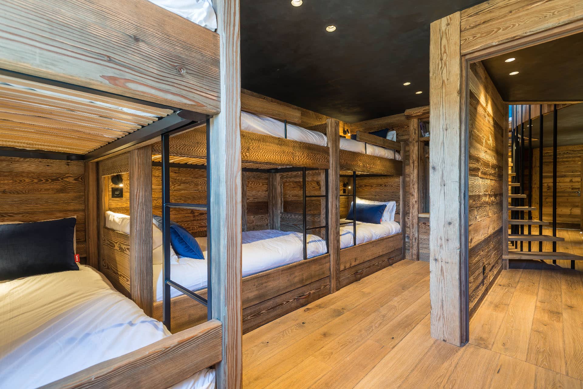 Dortoir de 15m² avec une décoration montagne moderne et ludique, comprenant 6 lits superposés de 90cm. Équipé d'une penderie, de rangements, et d'une fenêtre avec vue sur la montagne. Salle de bain indépendante, location chalet 2 Alpes