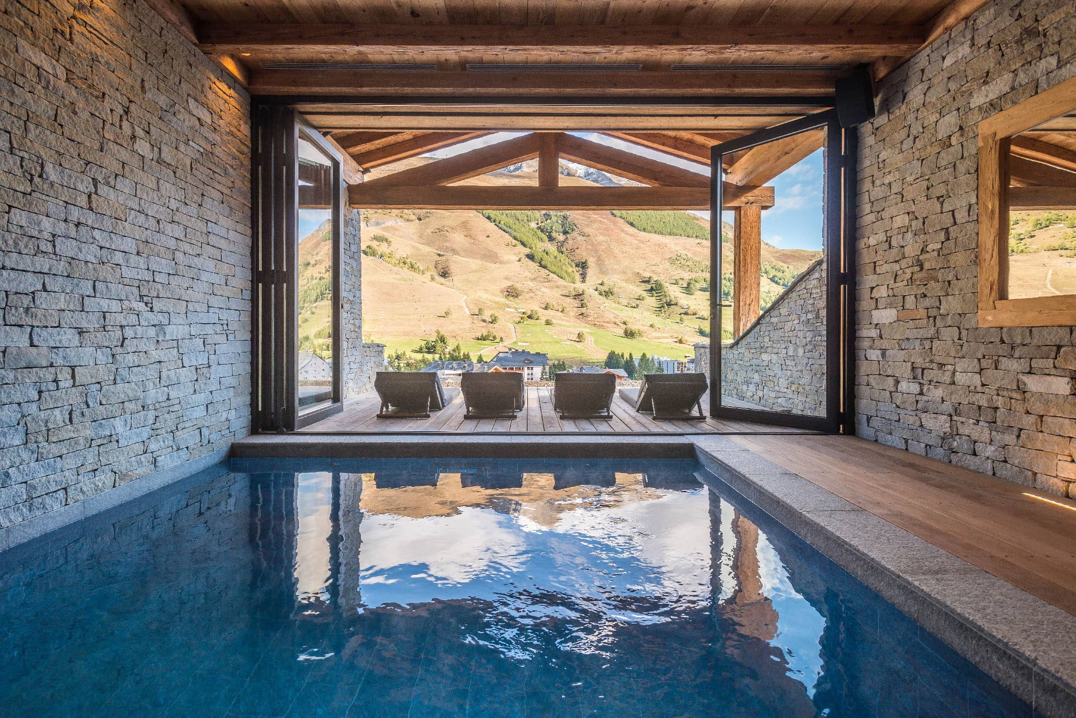 Piscine intérieure du chalet avec vue panoramique sur les montagnes. L’espace piscine est conçu pour offrir une vue imprenable sur le paysage alpin, combinant luxe et nature dans un cadre relaxant, location chalet 2 Alpes